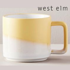 a yellow and white coffee mug sitting on top of a table with the words west elm above it