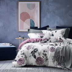 a bedroom with blue walls and purple flowers on the bedspread, along with an ottoman