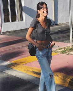 a woman is walking down the street with her hand in her pocket and smiling at someone