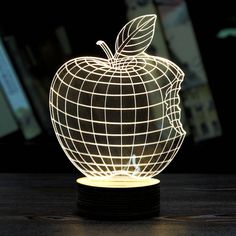 an illuminated apple sitting on top of a wooden table