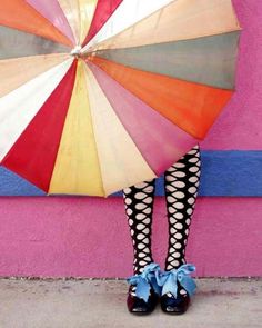 a woman in black and white polka dot tights holds an umbrella over her head