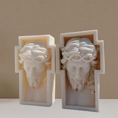 two white sculptures are sitting on a table next to each other and one is in the shape of a man's head