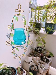 a blue glass hanging from the side of a wall next to potted plants on a table