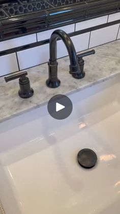 a white sink with black faucet and marble counter top