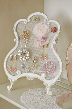 a white shelf topped with lots of earrings and brooches on top of it