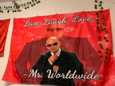 a man in a suit and sunglasses standing next to a red banner that says live laugh love mr world wide