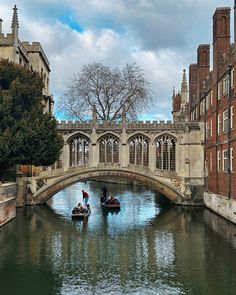 two small boats floating down a river next to tall buildings and a bridge with arched windows