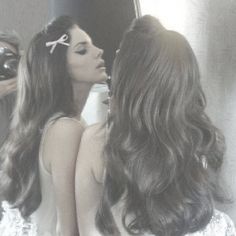 two beautiful women standing in front of a mirror kissing each other's foreheads