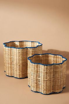 two woven baskets with blue trims on the sides, sitting side by side in front of a beige background