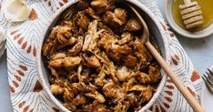 a bowl filled with chicken and sauce on top of a table next to utensils