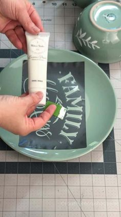 a person is holding a tube of toothpaste in front of a green plate