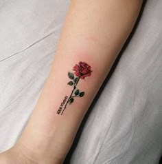 a small rose tattoo on the wrist with words written in cursive writing and a single flower