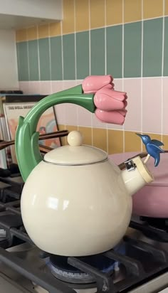 a tea pot with two birds on the handle is sitting on top of a stove