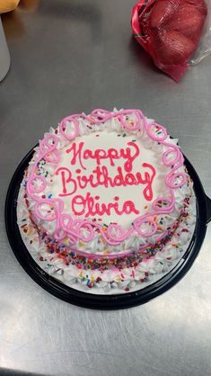 a birthday cake with pink frosting and sprinkles sitting on a table