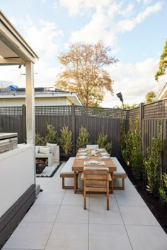 an outdoor dining area with table, chairs and grill in the back yard on a sunny day