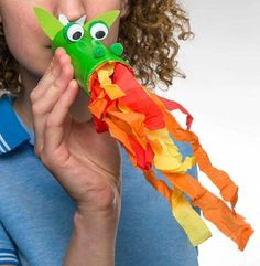 a woman holding up a colorful kite with googly eyes on it's face