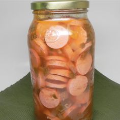 a jar filled with sliced carrots sitting on top of a green table cloth next to a white wall