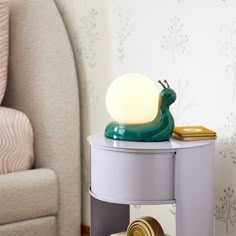 a green lamp sitting on top of a table next to a chair and wallpaper