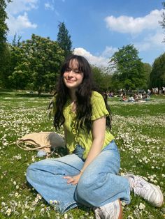 a woman sitting on the ground in a field full of daisies smiling for the camera