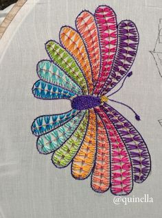 a colorful butterfly is on the side of a white piece of fabric with stitches in it