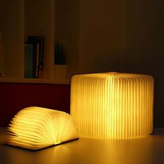 an open book sitting on top of a table next to a lit up light fixture