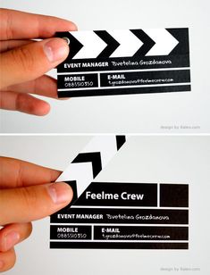 two business cards with black and white arrows on the front, one being held up by a person's hand