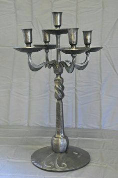 a silver candelabra with five candles on it's stand, in front of a white backdrop