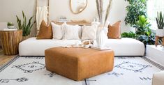 a living room filled with lots of white furniture and plants on the wall behind it