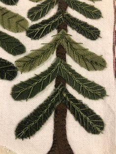 a close up of a piece of cloth with embroidery on it and a tree in the middle