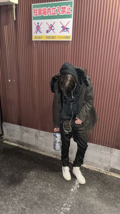 a man standing in front of a building with headphones on and holding a water bottle