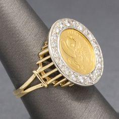 This fun piece is full of luck and luxe! The ring features a 5 yuan Panda coin, 1/20oz of .999 gold. The coin is bezel set and surrounded by a frame of round prong set diamonds. The diamonds measure 1.5 to 2.0mm, there are 21 of them leading to a calculated total weight of approximately 0.30cttw. The diamonds are H/I color and average I1 clarity with no eye visible inclusions. The coin stands a bit off of the finger with a frame of column like braces that hold up the coin. The bottom is open and Gold Coin Jewelry, Gold Coin Ring, Coin Stand, Ring With Diamond, Coin Ring, Gold Coin, Ancient Coins, Coin Jewelry, Bezel Diamond