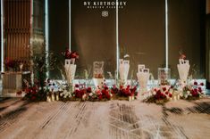 an arrangement of vases and flowers on display in front of a window at a wedding