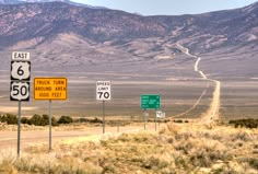 several road signs in the desert with mountains in the background