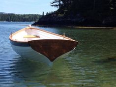 a small boat floating on top of a lake next to a shore covered in trees