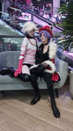 two women dressed up in costumes sitting on a couch next to an escalator