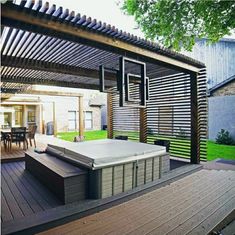 a hot tub sitting on top of a wooden deck under a pergolated roof