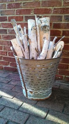 a bucket full of firewood sitting next to a brick wall