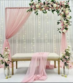 a white and pink wedding ceremony setup with flowers on the table, draping