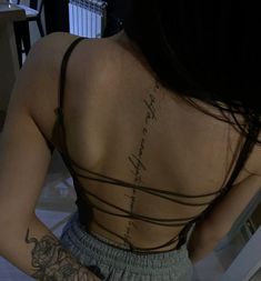 the back of a woman's body with writing on her left shoulder and right arm