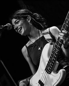 a woman singing into a microphone while holding a bass