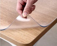 a hand that is touching the edge of a piece of glass on top of a table