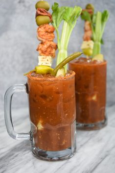 two mugs filled with food and garnishes on top of a table