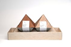 two wooden triangles with labels on them sitting in a wood holder against a white background