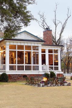 a large white house sitting on top of a grass covered field next to a forest