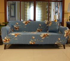 a blue couch with flowers on it in front of a mirror