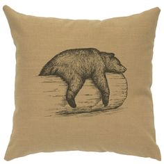 a brown pillow with a black bear on it's back and water in the background