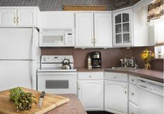 a kitchen with white cabinets and wood counter tops, including a cutting board on the island