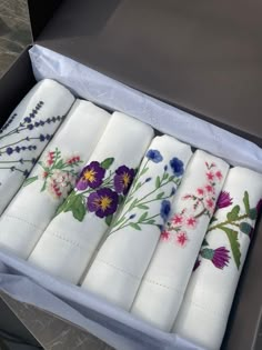 six white napkins with flowers on them in a box