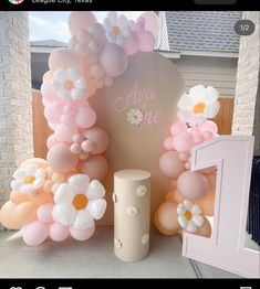 an arrangement of balloons and flowers on display in front of a sign that says age one