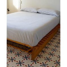 a bed sitting on top of a tiled floor next to a white wall and window